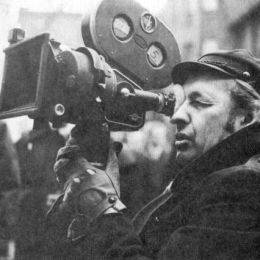 Czarno-biała fotografia przedstawiająca Andrzeja wajdę z kamerą filmową