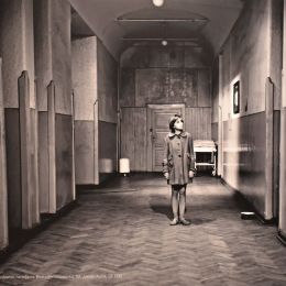 Kadr z filmu. Czarno-biała fotografia ukazująca dziewczynkę stojącą w korytarzu.