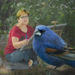 Na pierwszym planie duży niebieski ptak, na drugim wśród zieleni siedzi kobieta z obrazem w dłoniach 